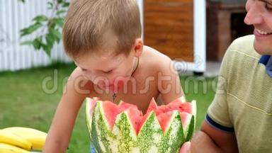 夏天，在花园里，爸爸和一个四岁的儿子切了一个西瓜，吃了它，玩得开心，一个男孩喜欢西瓜